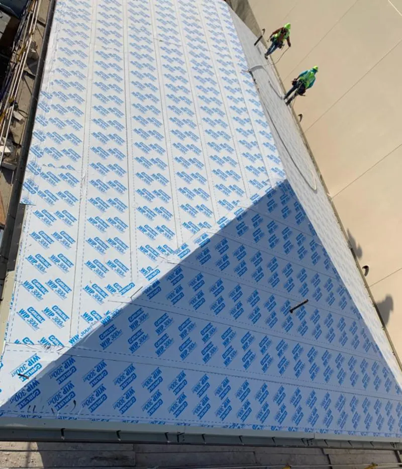 Professional roofers installing underlayment on a metal roof in Canandaigua